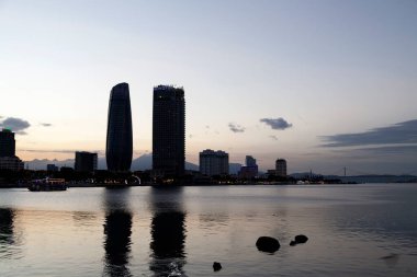 Da Nang, Vietnam - 20 Ağustos 2018: Tekne, Han Nehri üzerindeki Da Nang Şehir İdare Merkezi ve Novotel 'in önünden akşam karanlığında geçiyor..