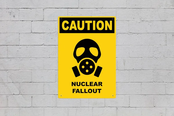 黄色的警示牌挂在砖墙上警告人们注意危险 在面板的中间 有一个防毒面具的符号 上面写着 核辐射 — 图库照片