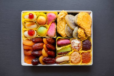 Ortasında beyaz metal tepsi, şekerli ve kuru meyveli..