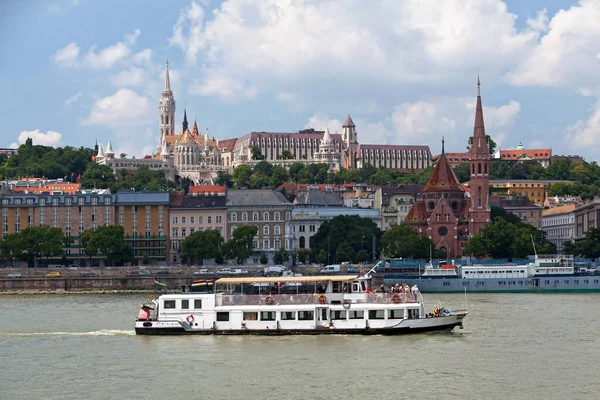 stock image Budapest, Hungary - June 21 2018: Boat passing before the Calvinist Temple of Szilagyi Dezso ter, Matthias Church, the Fisherman's Bastion.