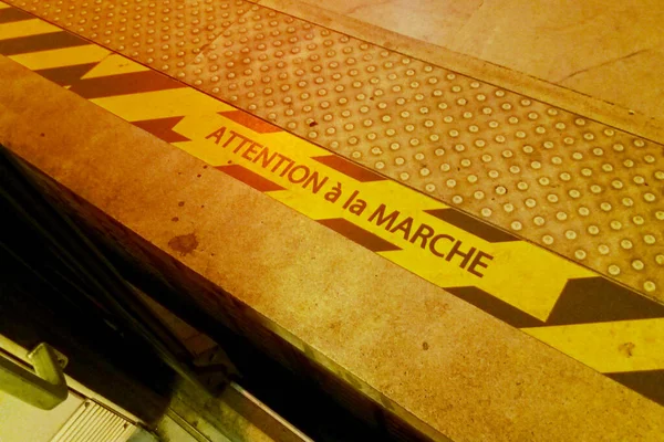在巴黎地铁的一个地铁站的边缘画有黄色和黑色条纹的警示牌 上面用法语写着 Attention Marche 意思是 — 图库照片