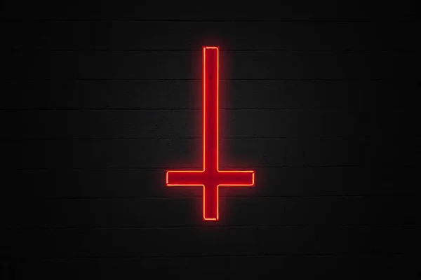レンガの壁の真ん中に取り付けられたセントピーターの十字架の下の赤い上向きに形作られたネオンライト — ストック写真