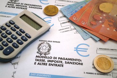 Bir İtalyan vergi formunun üzerine bir hesap makinesi ve biraz avro sikke ve banknotlar (Mod. F23).