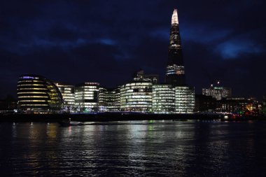 Belediye binası, kırıntı ve diğer ofis binaları hava karardıktan 30 dakika sonra karanlık gökyüzünde hala bulutları görebileceğiz. Binalar Thames Nehri 'ni de yansıtıyor..