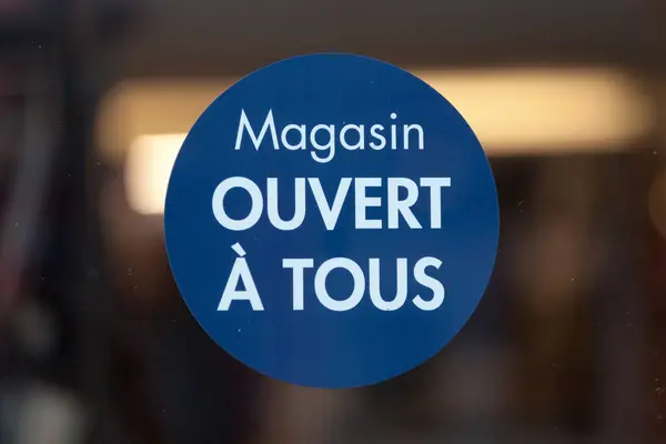Circular blue sign in the window of a shop saying in French \