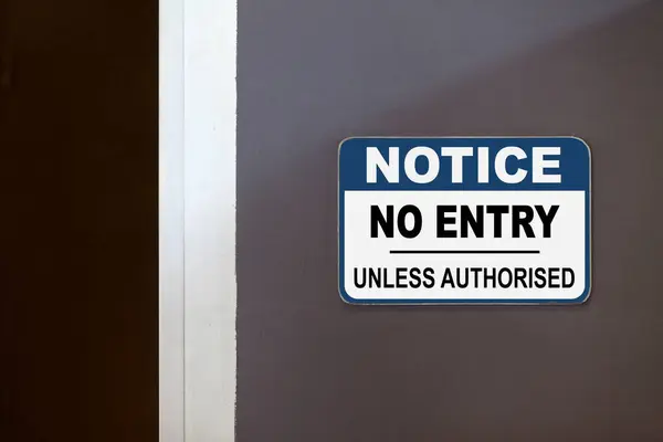 开着的门旁边有蓝白相间的告示 上面写着 非经授权不得入内 — 图库照片