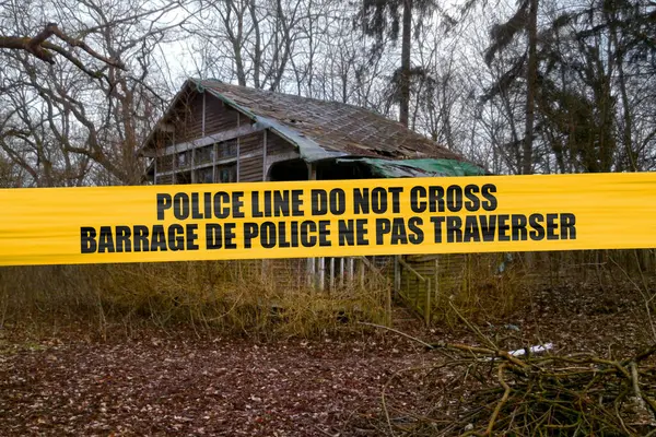 stock image Abandoned cabin in the woods with a police tape with written in it in English 