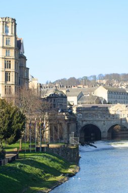 Pulteney Weir, Bath Market 'in karşısında ve arkasında Pulteney Köprüsü ile Avon Nehri' ni geçiyor..