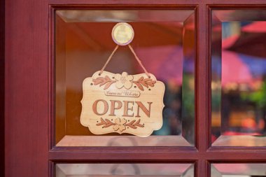 Bir dükkanın cam kapısında asılı ahşap tabela: 