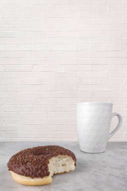 Kahve fincanının yanında çikolata kremalı bir çörek..