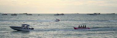 Pattaya, Tayland - 29 Temmuz 2006: Alacakaranlıkta eğlenen turistler, Pattaya plajı boyunca sürat teknesinin izlediği muz suyu kızağına biniyorlar.