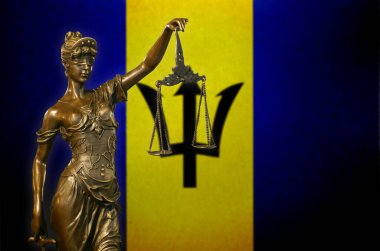 Antigua ve Barbuda bayrağı önünde küçük bronz bir Adalet Heykeli..