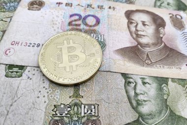 Bir yığın Çin Renminbi banknotunun üstünde altın bir Bitcoin 'e yakın plan..