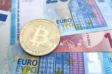Altın bir Bitcoin 'in üzerine yakın plan bir yığın Euro banknotunun üstüne.