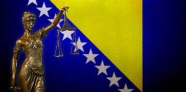 Bosna-Hersek bayrağı önünde küçük bronz bir Adalet Heykeli 'nin yakın çekimi.