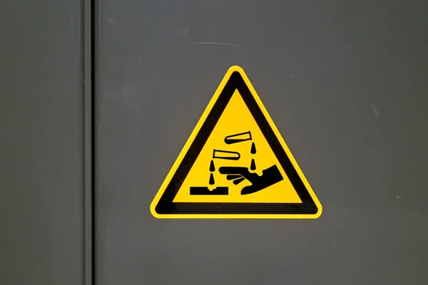 Yellow caution sign on a metal door warning about \