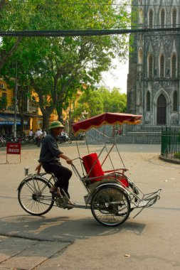 Hanoi, Vietnam - 22 Nisan 2009: Hanoi 'deki Aziz Joseph Katedrali' nin önünde müşterileri bekleyen çekçek sürücüsü.