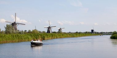Kinderdijk, Hollanda - 26 Ağustos 2017: Hollandalılar, Kinderdijk nehrinde yel değirmenlerinin yakınlarındaki mavnalarında seyir halindeler. Kinderdijk 'in yel değirmenleri 1997' den beri UNESCO Dünya Mirası oldu..