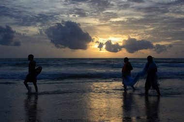 Phuket 'teki Patong plajında üç balıkçının silueti ile gün batımı.