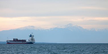 Thessaloniki, Greece - May 03 2019: Cargo ships in the Thermaic Gulf in anchorage in front of the snowcapped summit of Olympus Mount at sunset. clipart