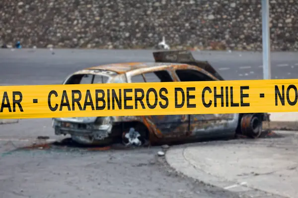 Car burnt by a pyromaniac with a police tape with written in it in Spanish \