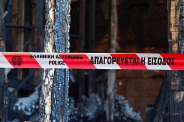 Athens, Greece - June 23 2017: House burnt to the ground by a pyromaniac with a police tape written in Greek. clipart