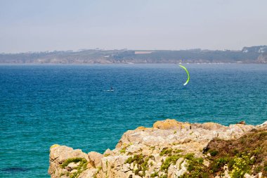 Kite surfer at the Anse des Blancs Sablons between the Pointe de Kermorvan (foreground) and the village of Illien (background). clipart