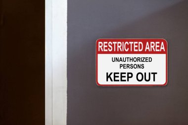 Koridorun kenarındaki kırmızı ve beyaz işaret levhasında 