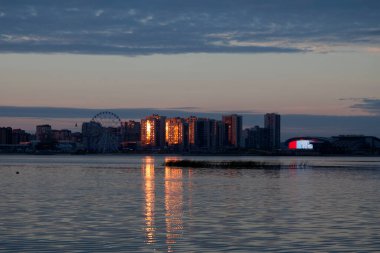 Günbatımının yansıması nehrin karşı yakasında, Kazan 'daki Arena ve Aquapark' ın yanındaki konut binalarında..