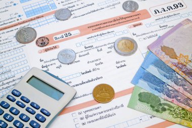 Bangkok, Tayland - 2005 Ekim 2018: Bir Tayland gelir vergisi formunun tepesinde bir hesap makinesi ve birkaç baht madeni para ve banknot.
