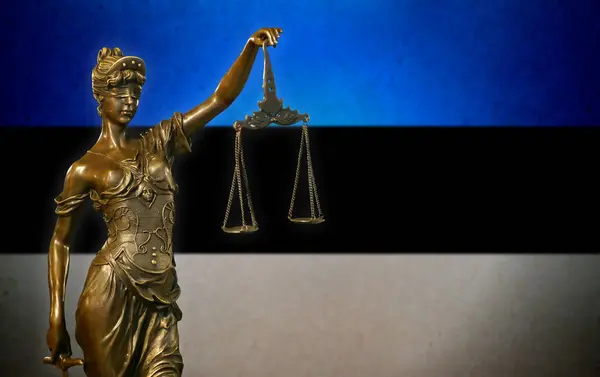 stock image Close-up of a small bronze statuette of Lady Justice before a Estonian flag.