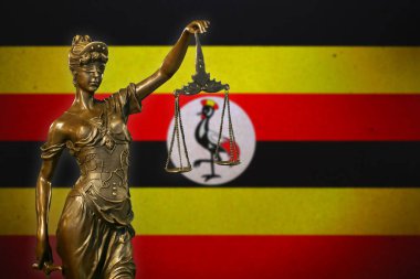 Uganda bayrağı önünde küçük bronz bir Adalet Heykeli..