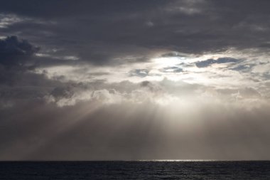 Bulutların arasından parlayan güneş ışığı, Reunion Adası 'ndaki Hint Okyanusu' na yansıyan kreusküler ışınların doğmasını sağlar..
