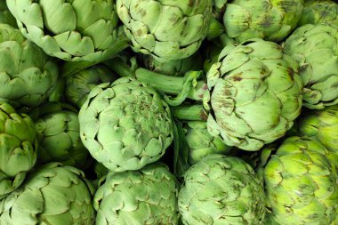 Close-up on a stack of artichokes for sale on a market stall.