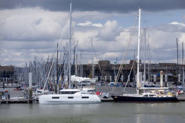 Larmor-Plage, France - August 06 2023: Boats moored at the Kernevel marina in Larmor-Plage with the Lorient Submarine Base behind. clipart