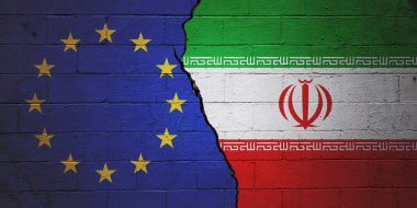 Solda Avrupa Birliği bayrağı, sağda İran bayrağı ile boyanmış tuğla duvar..