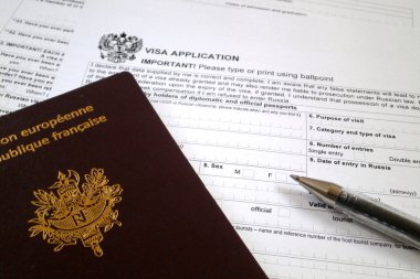  Rusya 'ya yönelik vize başvurusu formunun üstünde tükenmez kalem ve Fransız pasaportu var..