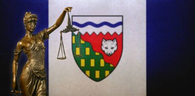 Kuzeybatı Toprakları bayrağı önünde küçük bronz bir Adalet Heykeli 'nin yakın çekimi (Kanada).