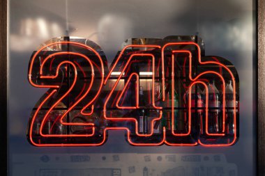 Berlin, Almanya - 14 Haziran 2019: Bir süperetin vitrininde kırmızı 24H neon ışığı.