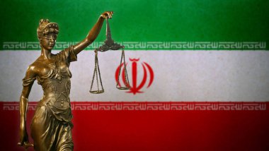 İran bayrağı önünde küçük bronz bir Adalet Heykeli..