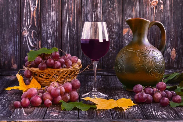 Bir Kadeh Kırmızı Şarap Saman Sepetinde Olgun Üzümler Koyu Ahşap — Stok fotoğraf