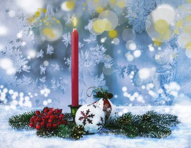 Kırmızı mum, Noel ağacı oyuncakları, Noel ağacı dalları, karlı bir pencere zemininde rowan. Bokeh 'le Noel kompozisyonu.
