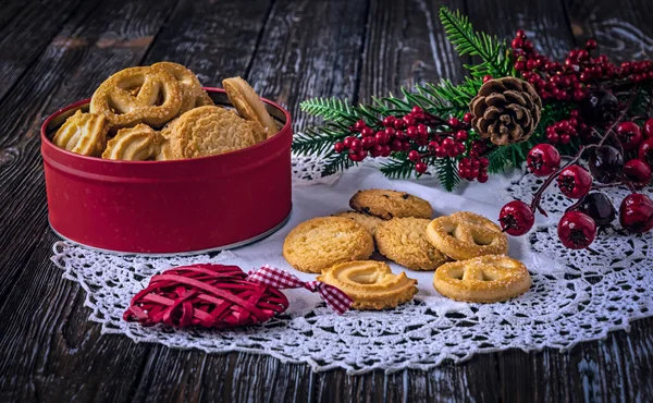 Cookies in a red box and on the table. Concept for National Cookie Day, December 4. Christmas branch and toy as decor.
