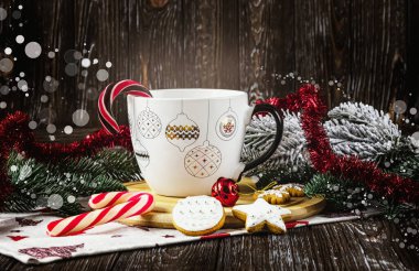 Noel süslemeli beyaz kupa masada lolipoplar, kurabiyeler, Noel baloları ve Noel ağacı dalları. Mutlu Noeller..