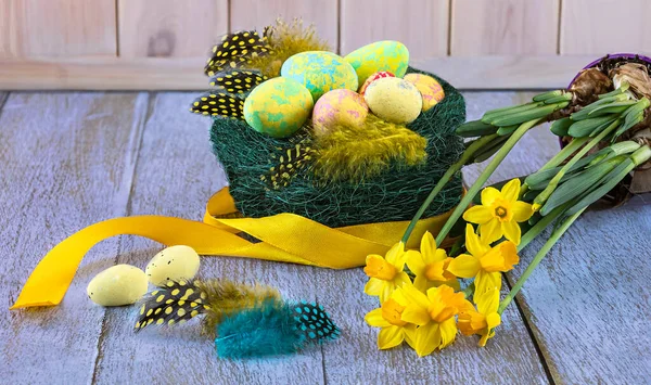 Hnízdo Velikonočními Vejci Peřím Žlutými Květy Narcisů Žlutou Stuhou Zblízka — Stock fotografie