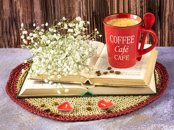 Still life with a red cup of coffee, books, gypsophila flowers and coffee beans. Candles as decor.