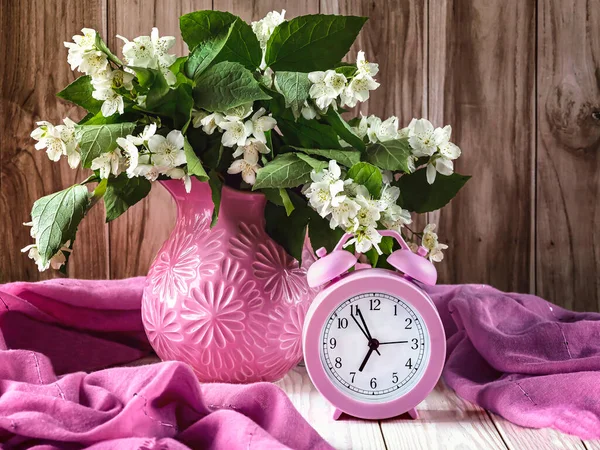 老式粉红闹钟和茉莉花束在木制背景粉红花瓶上 夏日清晨的概念 — 图库照片