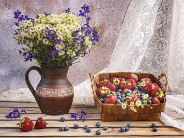 Yaz aylarında bir sepet çilek ve yaban mersini, pencere kenarında kır çiçekleri olan eski bir seramik vazo.