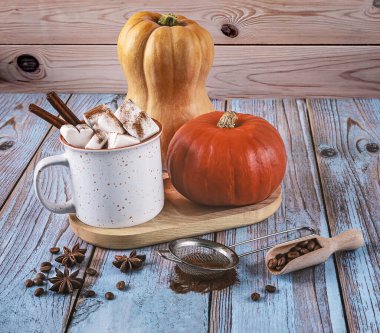 Lezzetli balkabağı aromalı latte beyaz seramik fincan, balkabağı, kahve çekirdekleri, tarçın ve ahşap masada yıldız anason..