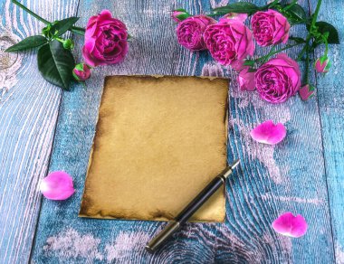 Eski model kağıt, mavi arka planda tüy kalem ve pembe şakayık çiçekli kalem. Aşk mektubu kavramı